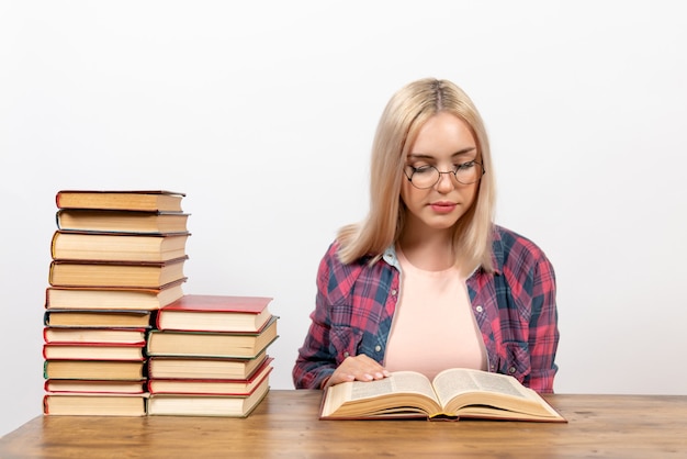 jeune femme assise avec des livres et lisant sur blanc