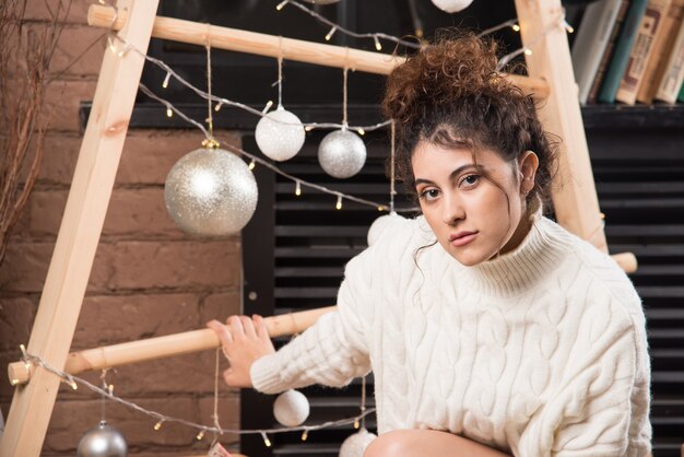 Jeune femme assise et posant près des boules de Noël dorées