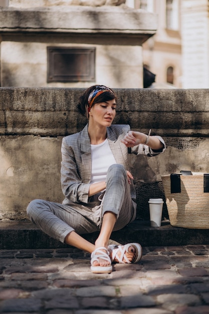 Photo gratuite jeune femme assise près de la fontaine