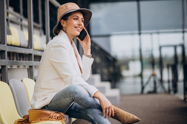 Jeune femme assise sur des sièges d'arène et parler au téléphone