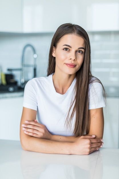 Jeune femme assise sur une table dans la cuisine.