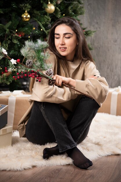 Une jeune femme assise sur un tapis moelleux avec des baies de houx de Noël .