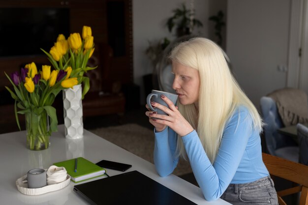 Jeune femme atteinte d'albinisme et tasse de café dans la cuisine