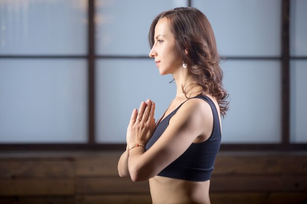 Jeune femme attrayante faisant le geste de Namaste, soirée de studio