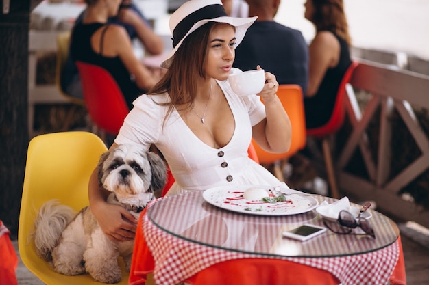 Jeune femme au bar avec un chien mignon en train de déjeuner