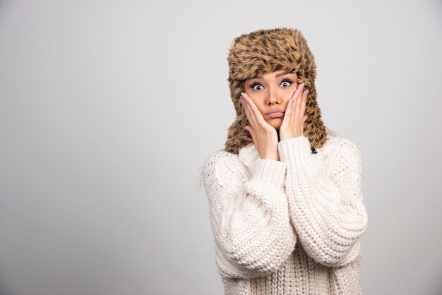 Une jeune femme au beau chapeau debout et posant.