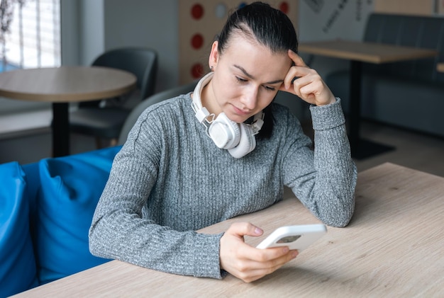 Une jeune femme au casque blanc et avec un smartphone