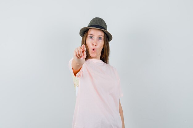 Jeune femme au chapeau t-shirt rose pointant la caméra et à la surprise