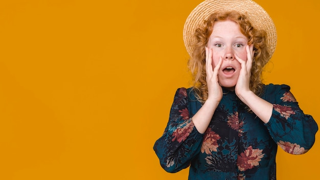 Jeune femme au chapeau touchant les joues et se demandant