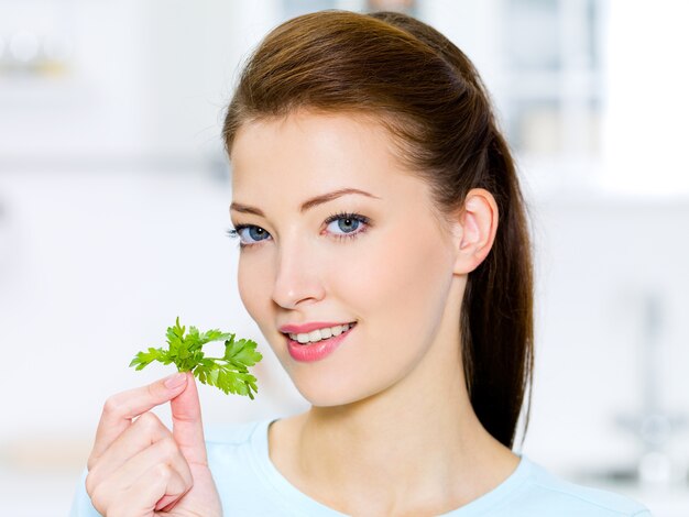 Jeune femme au fenouil vert à la main - sur la cuisine