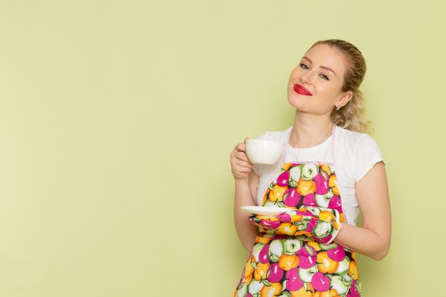 Jeune Femme Au Foyer En Chemise Et Cape Colorée Tenant Une Tasse De Thé Blanc Souriant Sur Vert