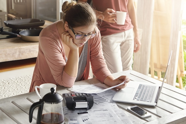 Jeune femme au foyer habillée avec désinvolture concentré sur la paperasse