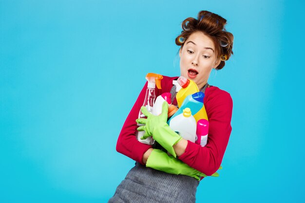 Jeune femme au foyer joyeuse en rose et gris détient des outils de nettoyage