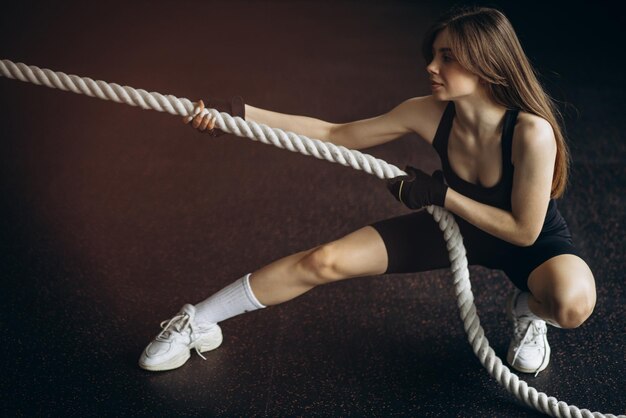 Jeune femme au gymnase tirant la corde de bataille