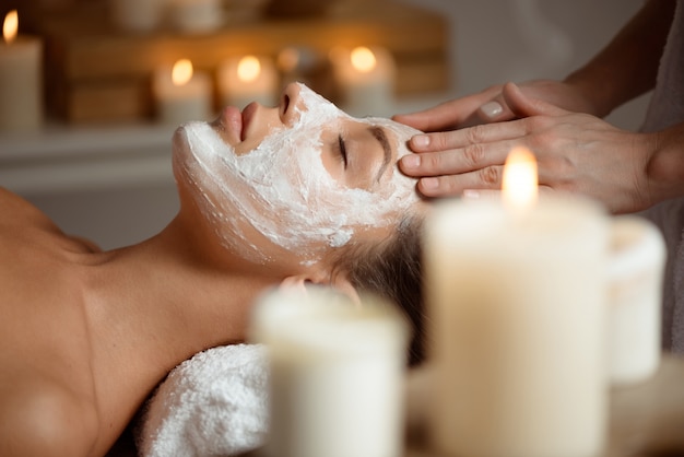 Jeune femme au masque pour le visage relaxant dans le salon spa.