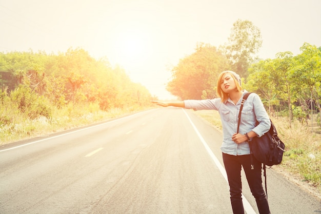 Jeune femme auto-stop sur une route