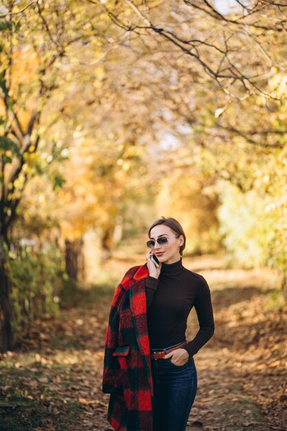 Jeune femme en automne parc à l&#39;aide de téléphone