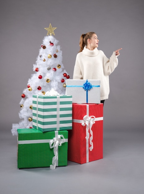 jeune femme autour de cadeaux de Noël sur fond gris