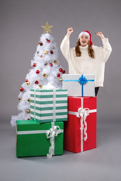 jeune femme autour de cadeaux de Noël sur fond gris