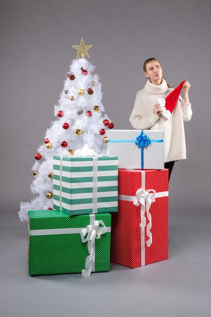 jeune femme autour de cadeaux de Noël sur fond gris