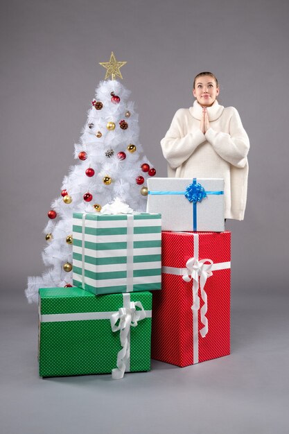 jeune femme autour de cadeaux de Noël sur fond gris