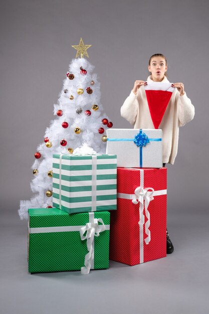 Jeune femme autour de cadeaux de Noël sur sol gris