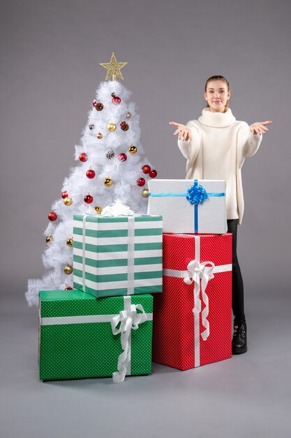 jeune femme autour des cadeaux de vacances sur gris