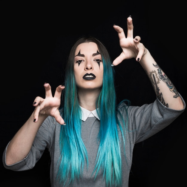 Jeune femme aux cheveux bleus et tatouage qui pose en studio