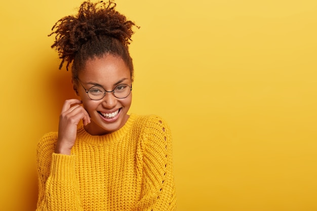 Jeune femme aux cheveux bouclés portant un pull jaune