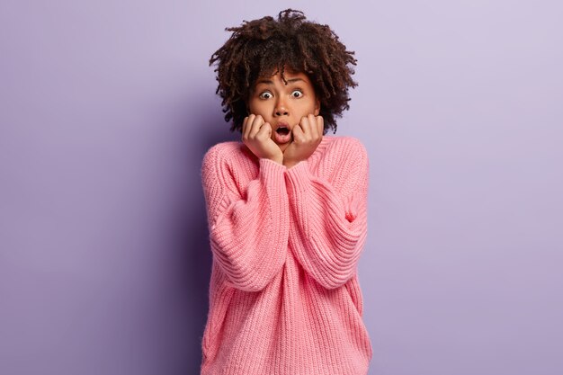 Jeune femme aux cheveux bouclés portant un pull rose