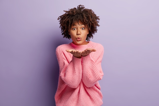 Photo gratuite jeune femme aux cheveux bouclés portant un pull rose