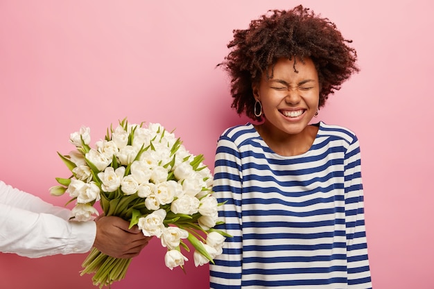 Jeune femme aux cheveux bouclés recevant un bouquet de fleurs blanches