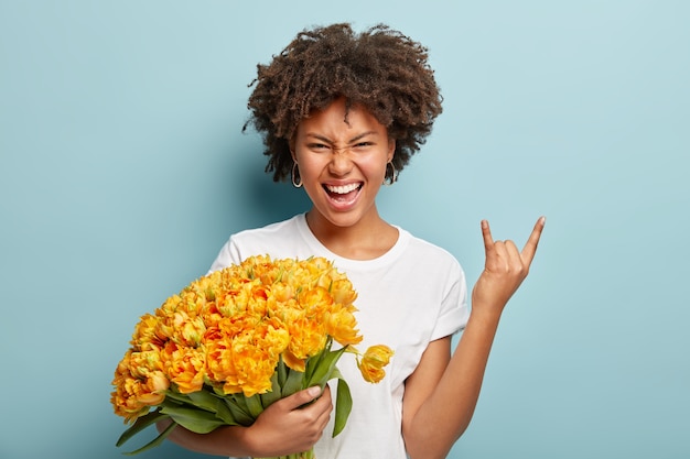 Jeune femme aux cheveux bouclés tenant le bouquet de fleurs jaunes