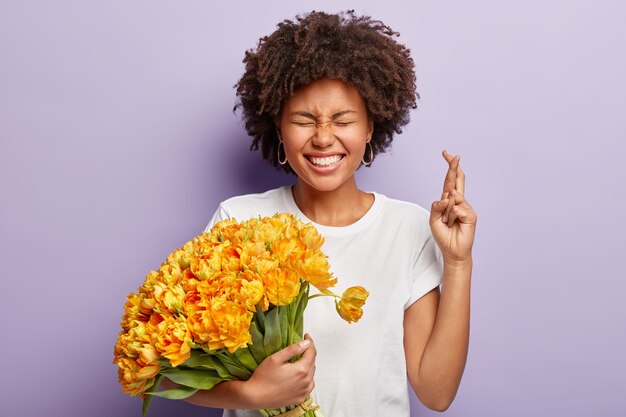 Jeune femme aux cheveux bouclés tenant le bouquet de fleurs jaunes