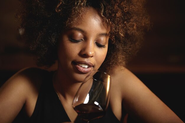 Jeune femme aux cheveux bouclés et un verre de vin rouge