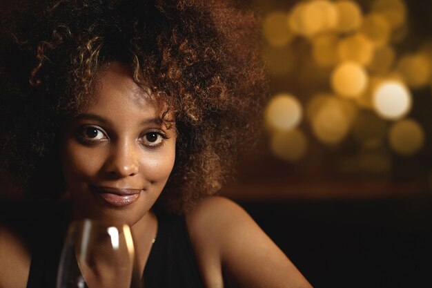 Photo gratuite jeune femme aux cheveux bouclés et un verre de vin rouge