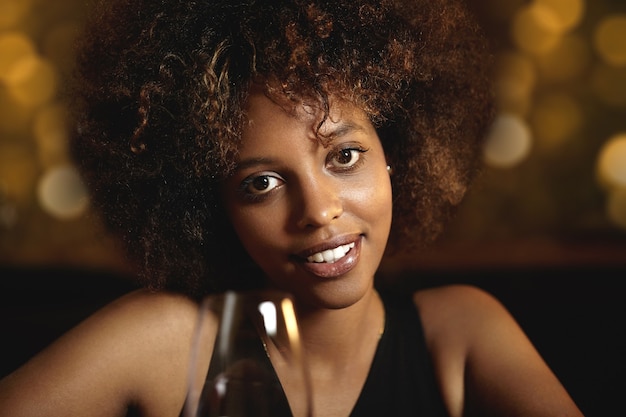 Photo gratuite jeune femme aux cheveux bouclés et un verre de vin rouge