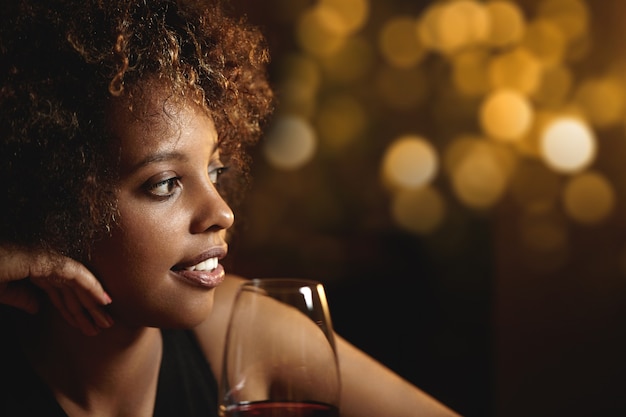 Jeune femme aux cheveux bouclés et un verre de vin rouge