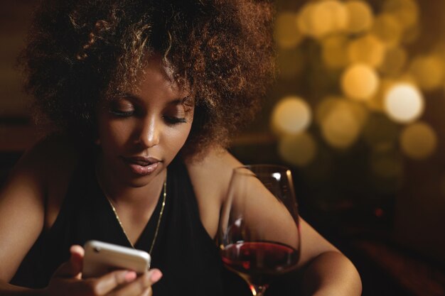 Jeune femme aux cheveux bouclés et un verre de vin rouge