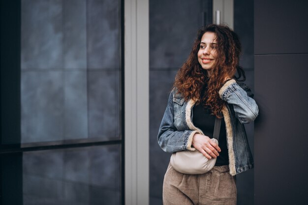 Jeune femme aux cheveux bouclés en veste en jean