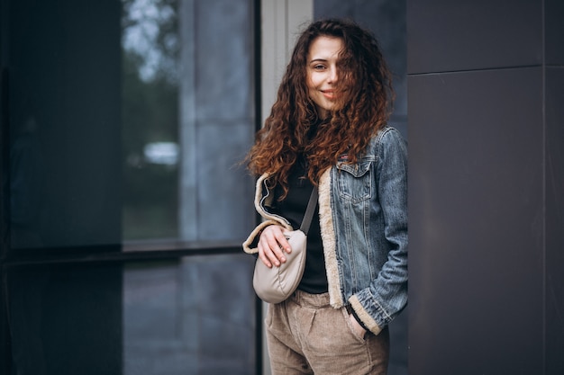 Jeune femme aux cheveux bouclés en veste en jean