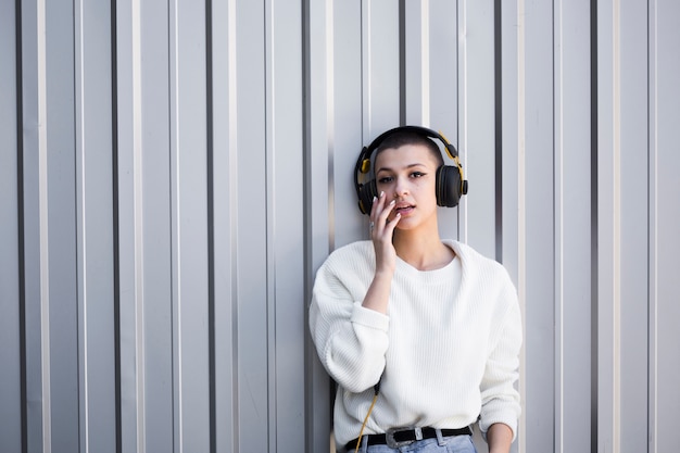 Photo gratuite jeune femme aux cheveux courts, écoutant de la musique tout en regardant la caméra