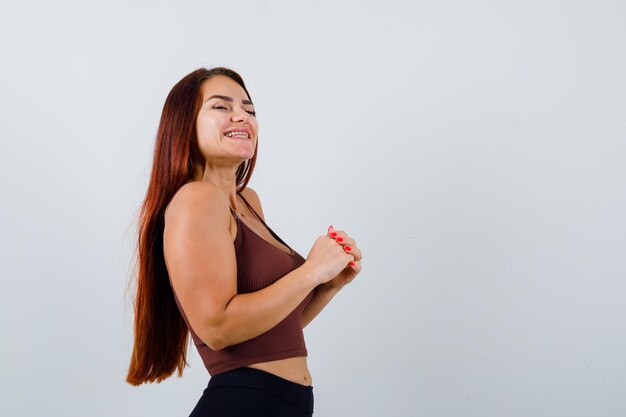 Jeune femme aux cheveux longs dans un haut court marron