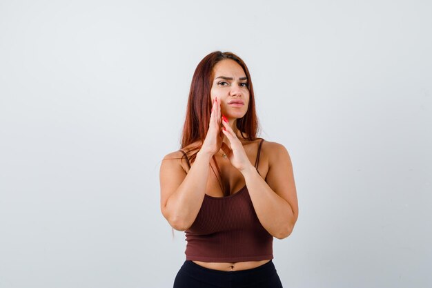 Jeune femme aux cheveux longs dans un haut court marron