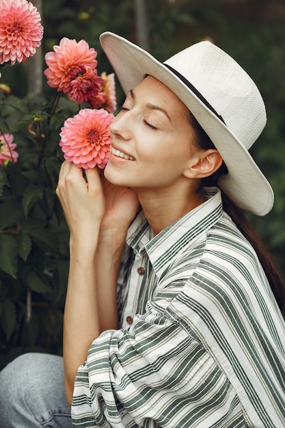 Jeune femme aux fleurs roses. Dame au chapeau. Fille dans un jardin.