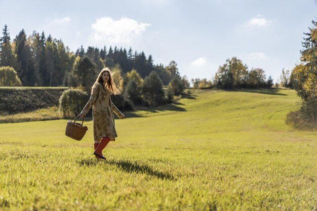 Jeune femme aux longs cheveux rouges dans une robe en lin cueillant des champignons dans la forêt dans le panier de liber