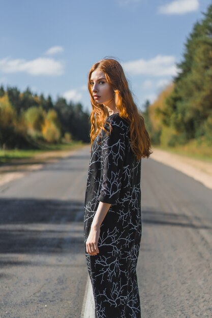 Jeune femme aux longs cheveux roux vêtue d&#39;une robe en lin dans un endroit naturel sur le fond
