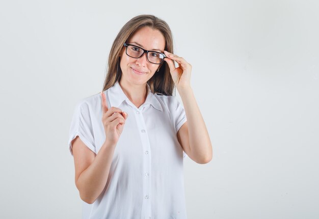 Jeune femme avertissement avec doigt en chemise blanche