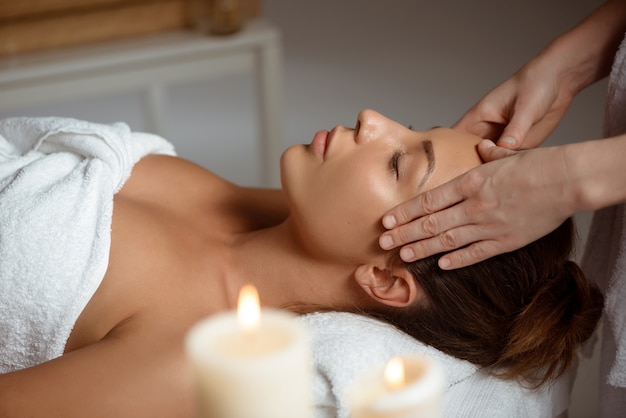 Jeune femme ayant le massage du visage relaxant dans le salon spa.