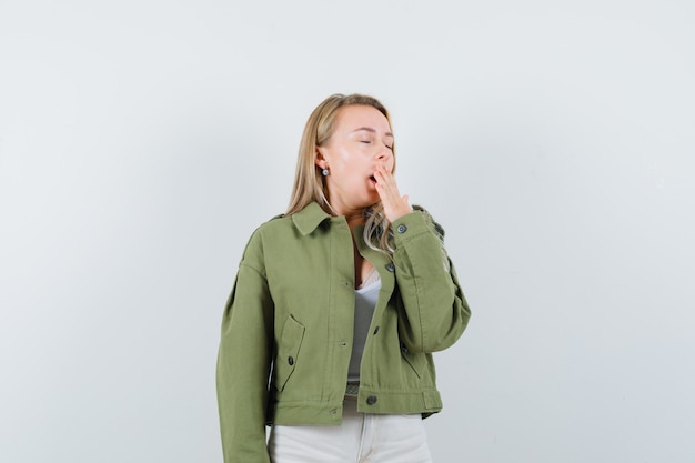 Jeune femme bâillant en veste, pantalon et à la recherche de sommeil. vue de face.